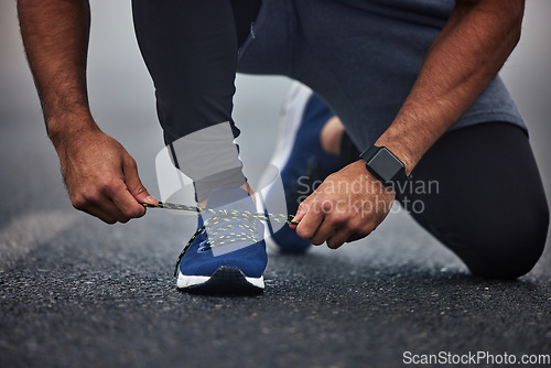Image of Man, hands and tying shoes on road for running, fitness or cardio workout on asphalt in the outdoors. Hand of male person, runner or athlete tie shoe and getting ready for sports training on street