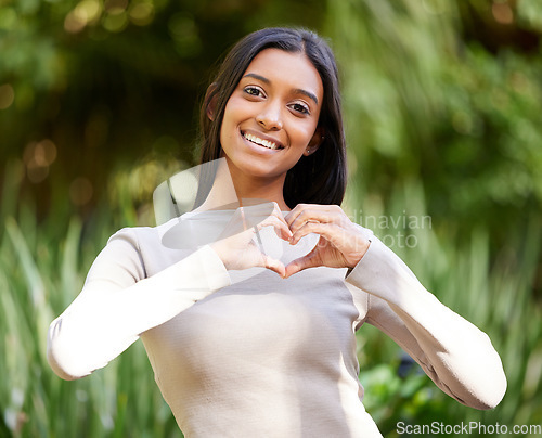 Image of Portrait, smile and woman with heart hands in nature for love, care and affection. Face, love hand gesture and Indian female person with emoji for kindness, empathy or romance, support and trust.