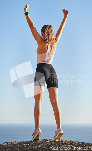 Image of Hiking success, fitness and a woman on a cliff to celebrate training achievement or health. Back, winning and an athlete with celebration on a mountain after a nature walk and cardio commitment