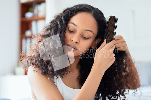 Image of Brushing hair, woman and morning routine at home with care and grooming. Bathroom, relax female person and curly hairstyle knots holding a brush in a house with haircare, natural beauty and youth