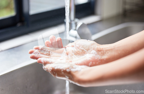 Image of Water, tap and person washing hands with soap for skincare, healthy dermatology and bacteria safety at home. Closeup, basin and cleaning hand with foam for hygiene routine, wellness and protection