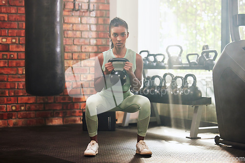 Image of Fitness, kettlebell and portrait of a woman in the gym doing strength legs and arms training. Sports, exercise and serious female athlete doing a strong squat workout with a weight in a sport center.