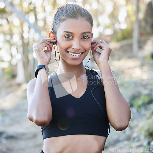 Image of Fitness, earphones and portrait of a woman in nature after running for race or marathon training. Sports, exercise and female athlete listening to music, radio or podcast for cardio workout in woods.