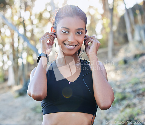 Image of Sports, portrait and woman with a earphones for music, radio or podcast while running in nature. Fitness, exercise and female athlete doing cardio workout for race or marathon training in the woods.