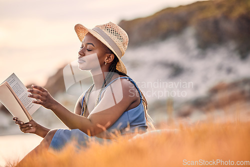 Image of Mountain, cliff and woman reading a story while relaxing outdoor on the grass at sunset in summer. Freedom, travel and calm African female person enjoying a novel or fantasy book on hill with peace.