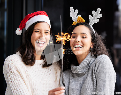 Image of Women friends, Christmas and sparkle stick with smile, home and celebration of festive holiday. Girl, woman and fireworks with light to celebrate for happiness, vacation or laughing with xmas bonding