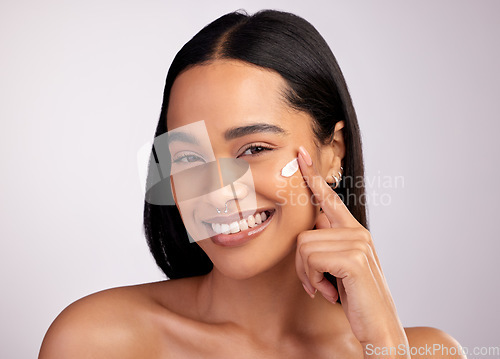 Image of Happy woman, portrait and face cream for skincare, beauty or cosmetics against a grey studio background. Female person or model smiling for lotion, creme or cosmetic moisturizer or facial treatment