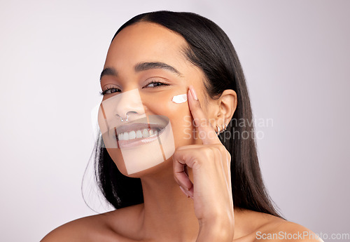 Image of Happy woman, portrait and skincare cream on face for beauty or cosmetics against a grey studio background. Female person or model smiling for lotion, creme or cosmetic moisturizer or facial treatment