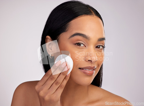 Image of Happy woman, face and cotton pad in skincare for makeup removal against a grey studio background. Portrait of female person cleaning or wiping product and cosmetics with swab for facial treatment