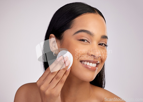 Image of Happy woman, cotton pad and cleaning face in skincare for makeup removal against a grey studio background. Portrait of female person wiping product, cosmetics or remove with swab for facial treatment