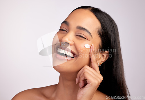 Image of Happy woman, portrait and skincare cream, product or beauty cosmetics on face against a grey studio background. Female person or model smiling with lotion, creme or moisturizer for facial treatment