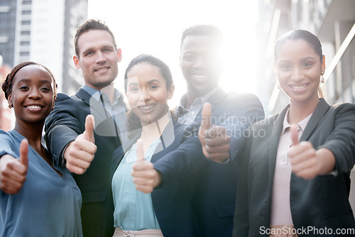 Image of Diversity, portrait of businesspeople and thumbs up smiling in a city background with a lens flare. Collaboration or teamwork, thank you or success and happy colleagues standing in urban outdoors