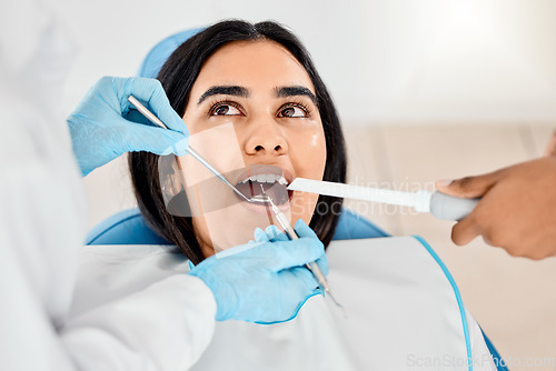 Image of Dentist, woman and patient at a clinic with medical and healthcare for teeth whitening. Mirror, orthodontist and female person with wellness and dental work tool in mouth with care and cleaning