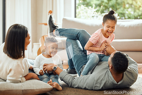 Image of Happy family, laughing and playing on floor in living room for fun bonding relationship together at home. Father, mother and children enjoying funny play time, laugh or holiday weekend in the house