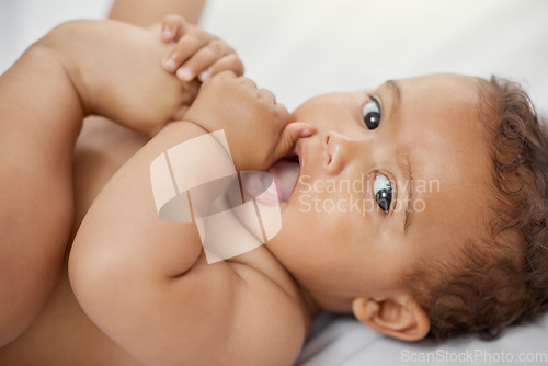 Image of Baby, portrait and child play with feet on bed in home having fun and enjoying time alone. Face, newborn and playing with foot, toes and cute infant, kid or toddler with growth, development and relax