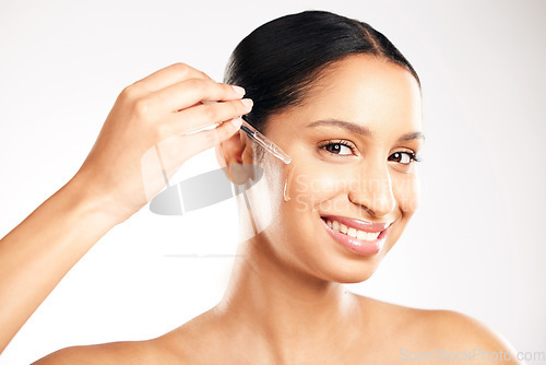 Image of Happy woman, face and serum for skincare, hydration or healthcare in retinol dermatology against a grey studio background. Portrait of female person with dropper for vitamin C, collagen or facial oil