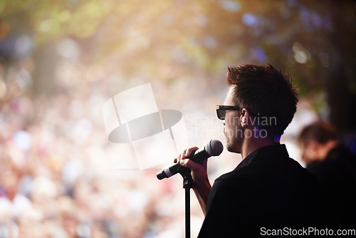 Image of Charismatic frontman. A singer performing on stage at an outdoor music festival.