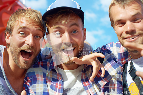 Image of Shout if youre having a good time. Portrait of three happy guys enjoying themselves at an outdoor festival.