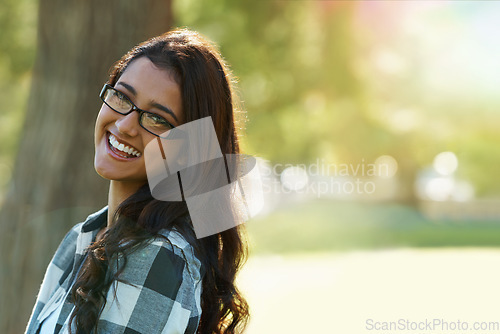 Image of Casual charm. A beautiful ethnic woman standing in a park wearing glasses.