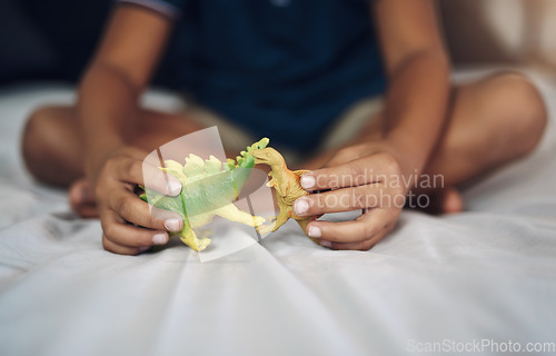 Image of I wish dinosaurs still existed. Cropped shot of an unrecognizable boy playing with dinosaurs while sitting on his bed.