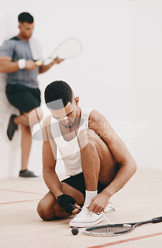 Image of The countdown to squash awesomeness. Shot of a young man tying his shoelaces before a game of squash.