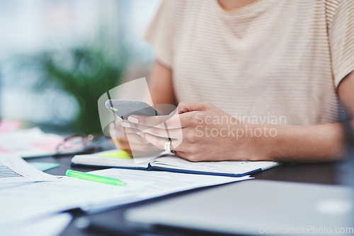 Image of The digital age demands one to stay connected. Closeup shot of an unrecognisable designer using a cellphone in an office.