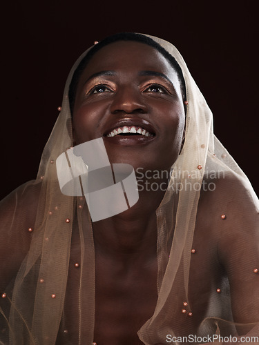 Image of Things are looking up. Studio shot of an attractive young woman posing in traditional African attire against a black background.