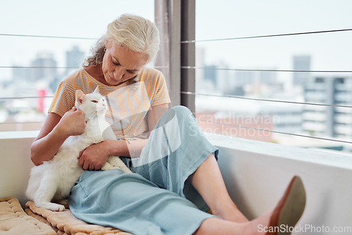 Image of Cuddles keep the heart content. Shot of a mature woman spending quality time with her cat on the balcony at home.