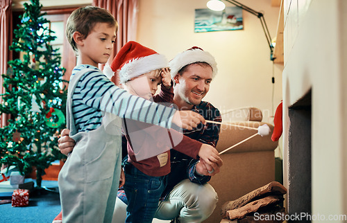 Image of Nothing says Christmas Eve like marshmallow toasties. Shot of two adorable little boys roasting marshmallows by the fireplace with their father at Christmas.