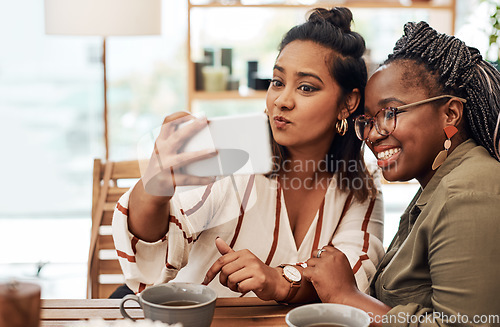 Image of Just call us the selfie queens. Shot of two young women taking selfies at cafe.