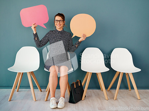 Image of I speak my mind all day. Studio portrait of an attractive young businesswoman holding up speech bubbles while sitting in line against a grey background.