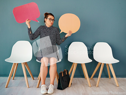 Image of I dont know whos right either. Studio portrait of an attractive young businesswoman holding up speech bubbles while sitting in line against a grey background.