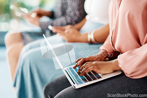 Image of This is the new way of taking notes. Cropped shot of a group of unrecognizable businesswomen using wireless technology while sitting in line in a modern office.