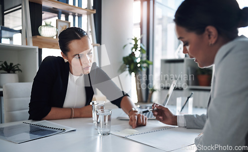 Image of Were going over the fine print together. Cropped shot of two attractive young businesswomen filling out paperwork together inside an office.