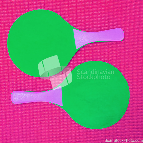 Image of Simple yet a great game to play. High angle shot of two green table tennis rackets placed on top of a pink background inside of a studio.