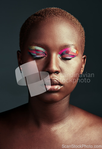 Image of Who needs black and white when you can shine in color. Cropped shot of a beautiful woman wearing colorful eyeshadow while posing against a grey background.