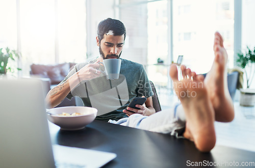 Image of I have a lot in my feed. Shot of a man using his cellphone while having breakfast at home.