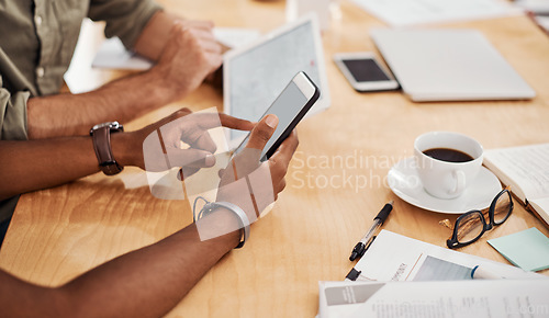 Image of Connected to business. Closeup shot of a two unrecognisable businessmen using a cellphone and digital tablet in an office.