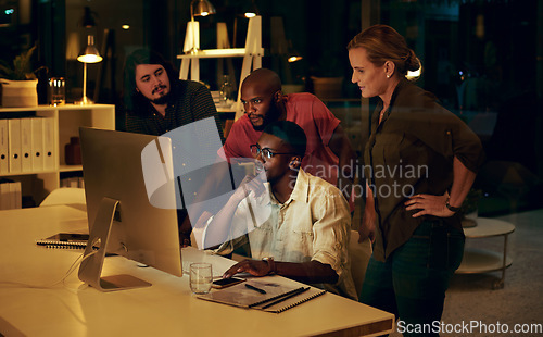 Image of Im sure we can get this done by the end of the night. Shot of a group of businesspeople looking at something on a computer in an office at night.