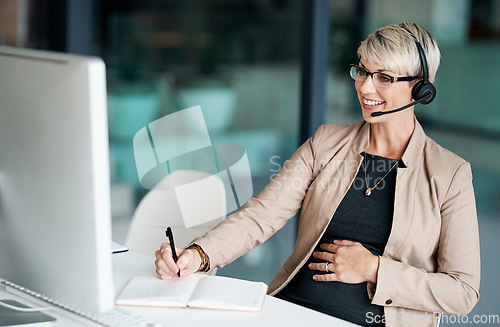 Image of Providing quality support that customers can appreciate. Shot of a pregnant businesswoman wearing a headset while writing notes in an office.