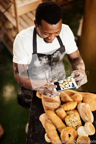 Image of This picture is for todays online baking tips. Cropped shot of a male baker taking a picture on his cellphone of a selection of freshly baked bread.