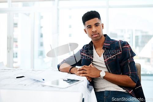 Image of Dedicated to delivering the best quality designs. Portrait of a young man going over blueprints in a modern office.