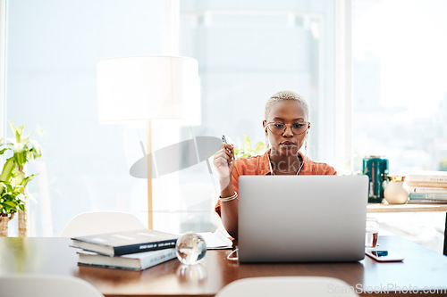 Image of The most effective way to do it is simply to do it. Shot of a young businesswoman wearing earphones while working on a laptop in an office.