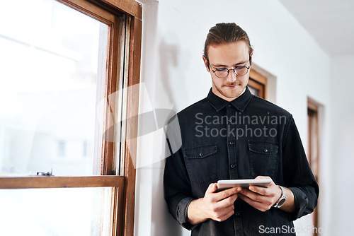 Image of I can achieve anything. Cropped shot of a handsome young businessman standing and using a tablet in his office alone.