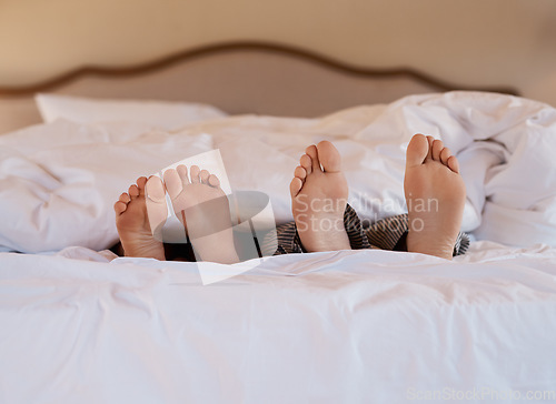 Image of I belong next to you. Shot of an unrecognizable couples feet poking out under the sheets while lying in bed.