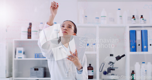 Image of Science is about answering many questions. Shot of a young scientist writing notes on a glass wall in a lab.