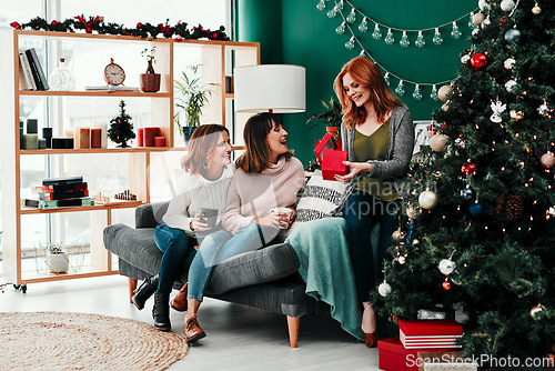 Image of You guys shouldt have. Shot of three attractive middle aged women opening presents together while being seated on a sofa during Christmas time.