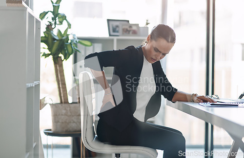 Image of These long hours are starting to negatively affect her health. Cropped shot of an attractive young businesswoman suffering from back pain while working inside her office.