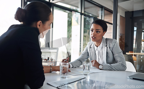 Image of Were both on the same page today. Cropped shot of two attractive young businesswomen working together inside a modern office.