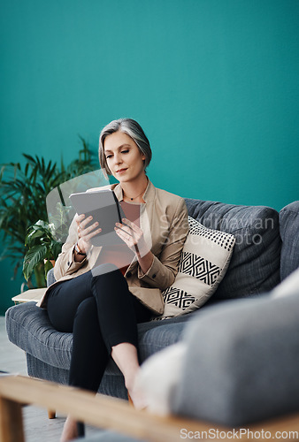 Image of Analysing the data correctly. Cropped shot of an attractive mature businesswoman sitting alone and using a tablet in her home office.